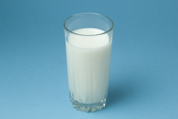 A glass of cow milk on a blue background.