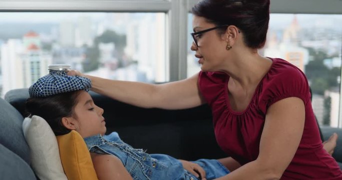 Woman Treating Fever On Sick Female Child At Home