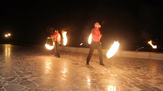 Men artists twist fiery circles on a fire show.Men does a fire performance.Fire show amazing at night.