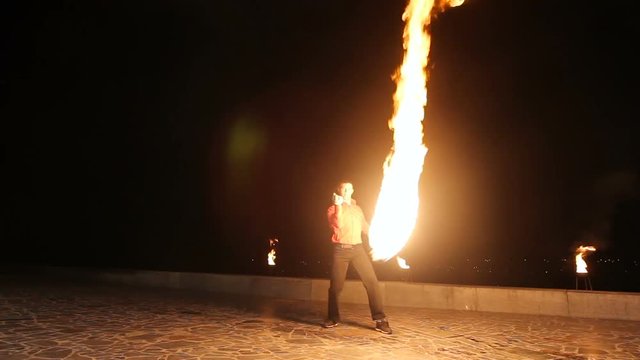 Artist man rotates the fireball.Man twist fiery circles on a fire show.Man does a fire performance.Fire show amazing at night.