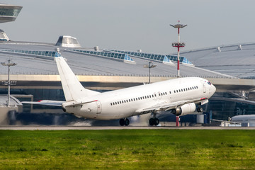 Fototapeta na wymiar White modern passenger twin-engine airplane taking off. Airport terminal at the background.
