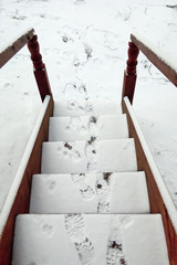 Snow and footprints on the wooden stairs of the village house