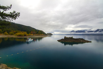 Fototapeta na wymiar Peaceful autumn landscape, boat on blue Lake Hawea near Albert Town and Wanaka, New Zealand