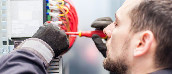 Closeup of electrician engineer works with electric cable wires
