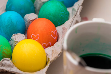 Colored Easter eggs next to some dye in a cup