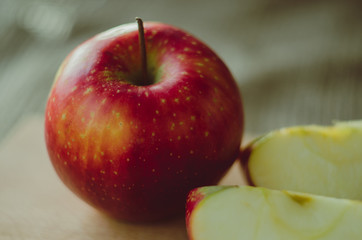 Close up of a sliced red apple on a wooden table.