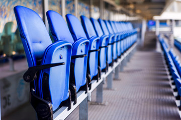 Empty blue plastic chairs in a row at the football stadium.
