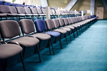 Many comfortable chairs in empty conference hall. Selective focus. Different from others.