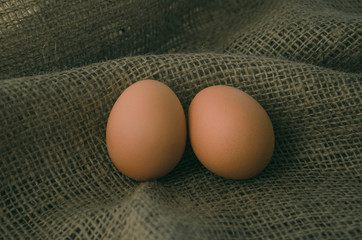 two chicken eggs on brown burlap