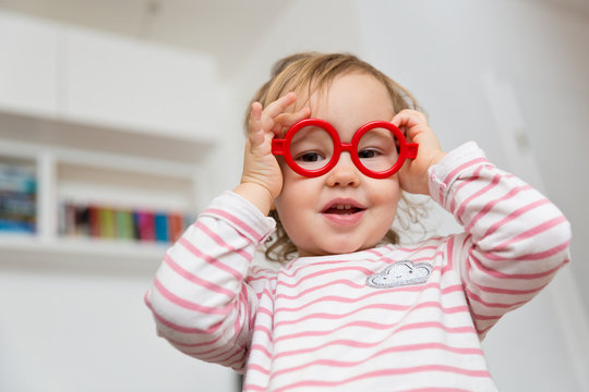 Toddler girl playing with plastic glasses