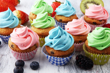 Fototapeta na wymiar Tasty cupcakes on wooden background. Birthday cupcake in rainbow colors