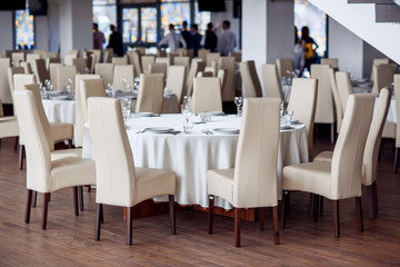 Serving a festive round table with white elegant chairs for a festive dinner.