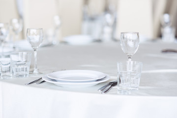 Sparkling glassware stands on round table prepared for holiday dinner. Champagne glasses on the celebration table.