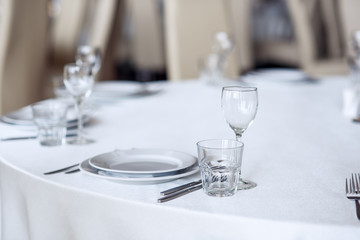 Sparkling glassware stands on round table prepared for holiday dinner. Champagne glasses on the...