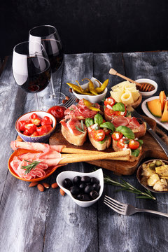 Italian antipasti wine snacks set. Cheese variety, Mediterranean olives, pickles, Prosciutto di Parma, tomatoes, artichokes and wine in glasses