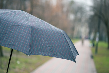 Close-up of dark umbrella during rain.