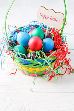 Image of basket with colorful eggs on empty blue background on wooden table