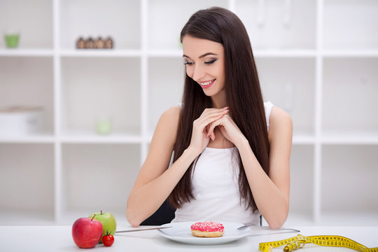 Dieting concept. Young Woman choosing between Fruits and Sweets