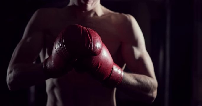 Boxer puts on boxing gloves. Male fighter putting his gloves on, in slow motion. Kickboxer getting ready to train putting on gloves