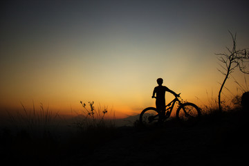 silhouette of a male mtb rider standing at sunset with volcanoes in the background