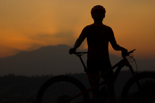 close up silhouette of a male cyclist at sunset with volcanoes in the background in Mexico