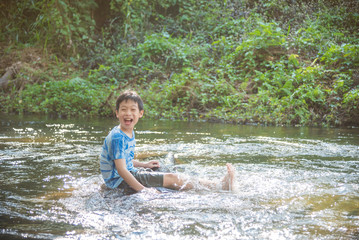 Young asian boy smiling while palying in the river