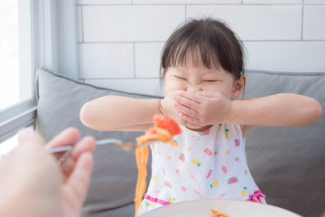Little asian girl refuse toeat tomato in spagethi from her mother - obrazy, fototapety, plakaty