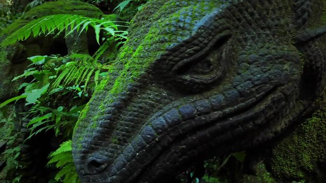 Moss covered Komodo dragon sculpture in Ubud Monkey forest, Bali, Indonesia. Tropical jungle nature and Hindu temple conservation area