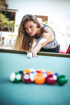 Beautiful woman is playing the billiards