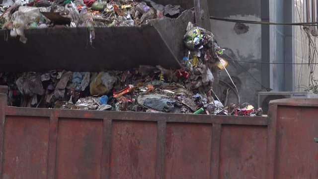 Front end loader shovels piles of garbage onto truck in New Delhi, India 