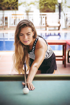 Beautiful woman is playing the billiards