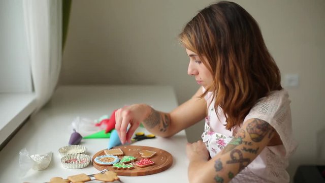 a young woman in the kitchen paints ginger Christmas gingerbread