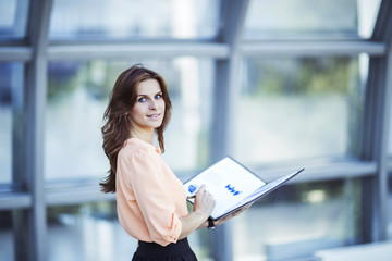 Fototapeta premium successful business woman with financial documents standing near a large window in a modern office