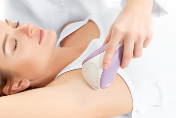 Obraz na płótnie Canvas Beautician giving epilation laser treatment to woman on underarm