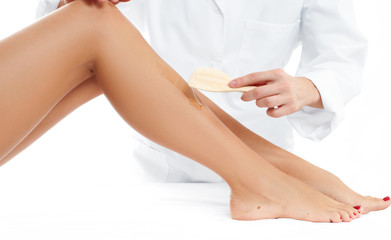 Obraz na płótnie Canvas Beauty Spa. Hair removal cosmetology procedure. Beautician waxing female legs