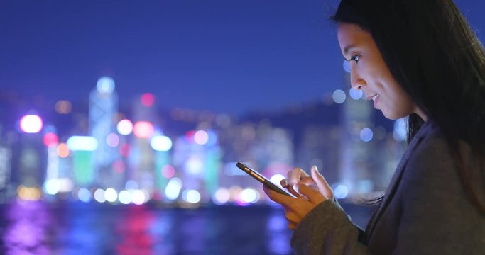 Business woman using cellphone in Hong Kong city at night