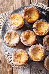 Pastel de nata with sugar powder close-up on the table. vertical top view