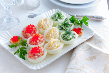 Festive serving of stuffed eggs with filling options - red, yellow, green. Selective focus, horizontal