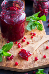 Cowberry jam in a glass jar on a wooden board, selective focus