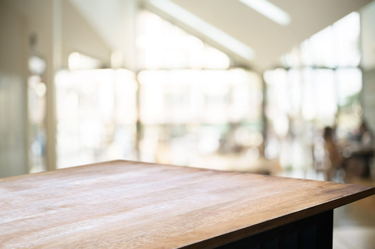 empty wooden desk over blurred montage coffee shop cafe / restaurant background