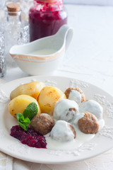 Meatballs with cream sauce and cranberry jam, on a white plate, selective focus