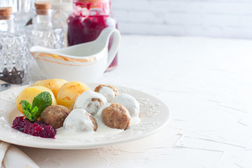 Swedish meatballs with cream sauce, boiled potatoes and cranberry jam, horizontal, copy space
