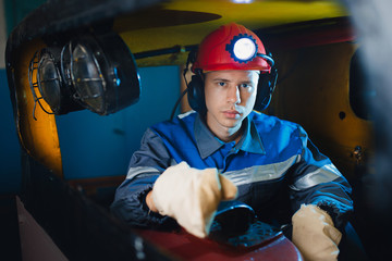 young miner man underground in mine for coal mining in overalls is busy with work, repairing...