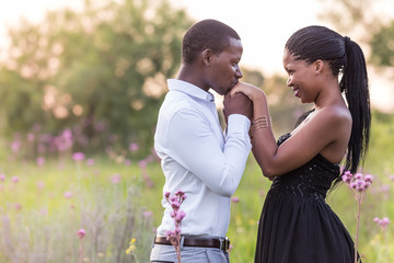 Young African couple in romantic embrace in a field. Young lovers in a field of flowers.