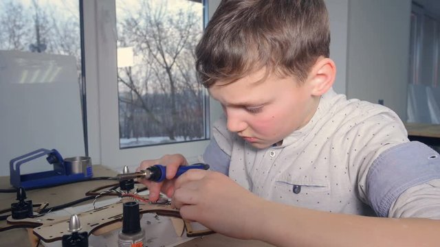 School boy is soldering drone.