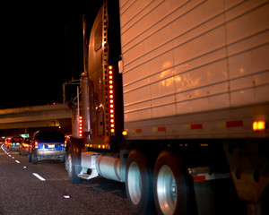Fototapeta na wymiar Big rig semi truck with reefer trailer move on the night road in reflecting lights