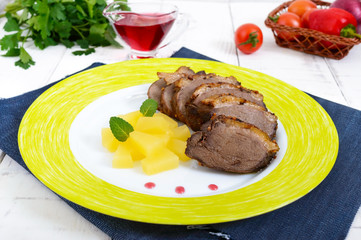 Duck breast Magret with pieces of pineapple on a ceramic plate on a white wooden background. French traditional meat dish. Christmas menu. Festive kitchen.