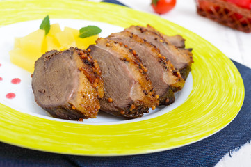 Fototapeta na wymiar Duck breast Magret with pieces of pineapple on a ceramic plate on a white wooden background. French traditional meat dish. Christmas menu. Festive kitchen.