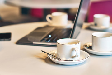 Busy morning with a laptop and many empty coffee or tea cups on the table