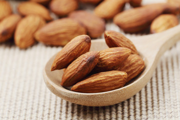 Close up of dry almonds nuts in a wooden spoon